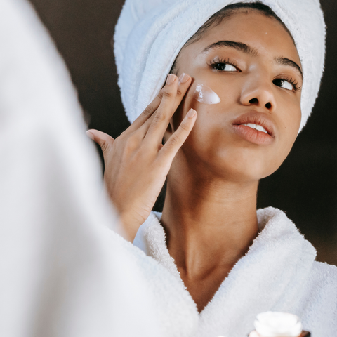 Woman wearing a bathrobe applying face cream