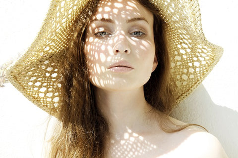 Femme qui protège ses cheveux du soleil avec un chapeau