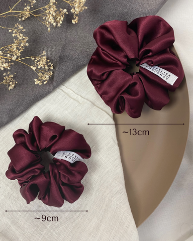 Two burgundy scrunchies (hair accessories) next to each other