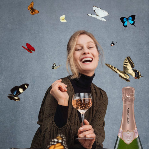 Hattingley Valley Sparkling Rosé Wine Pairings, Image of Woman laughing surrounded by butterflies, holding a glass of Hattingley Rosé