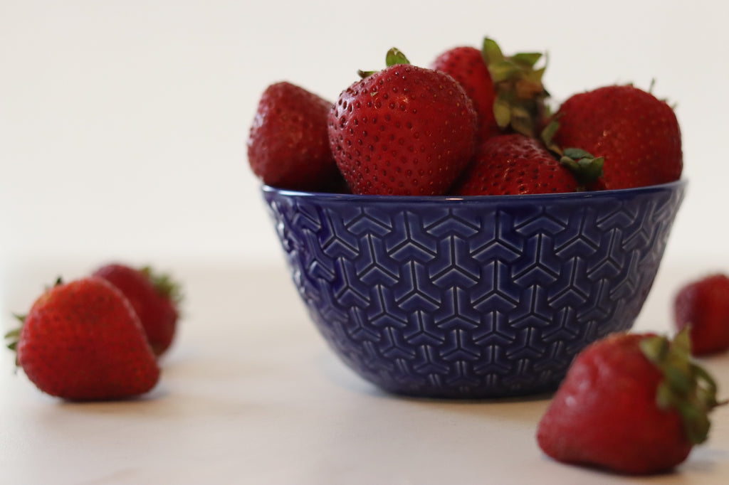 Strawberries in a bowl with a white background. Taken by Healthful Seasons