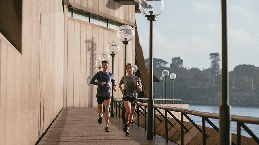 male and female jogging in sunlight along waterfront