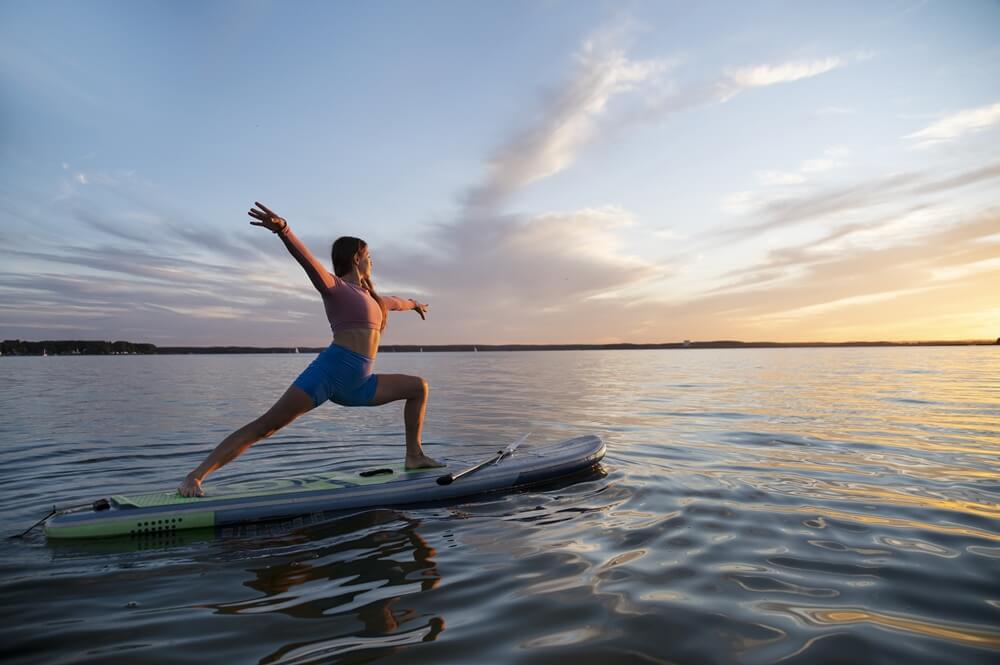 side-view woman doing yoga on a paddleboard