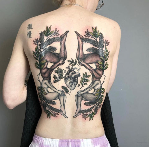 Four women's bodies with foliage are seen tattooed on a client's back.