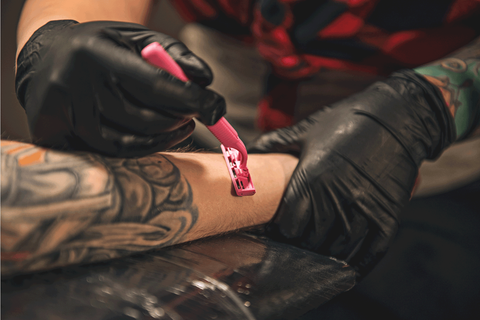 Tattoo artist shaving arm