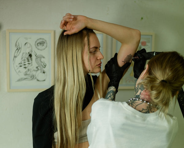 Woman being tattooed on the arm