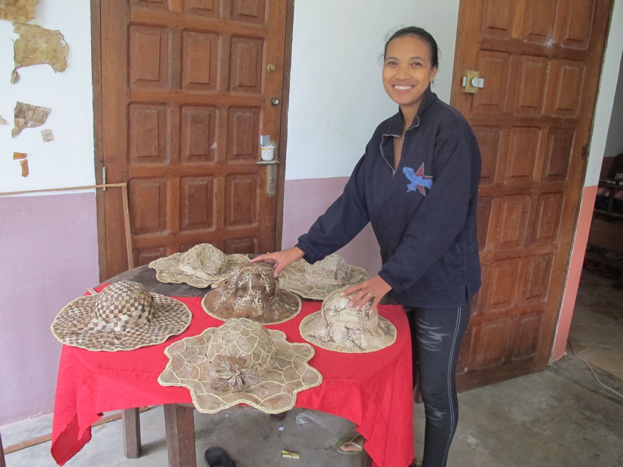 Lalaina stands next to a table of intricate wild silk hats