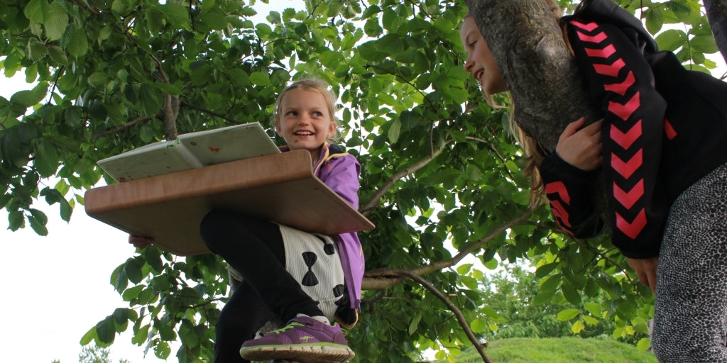 Mädchen machen Hausaufgaben auf einem Baum