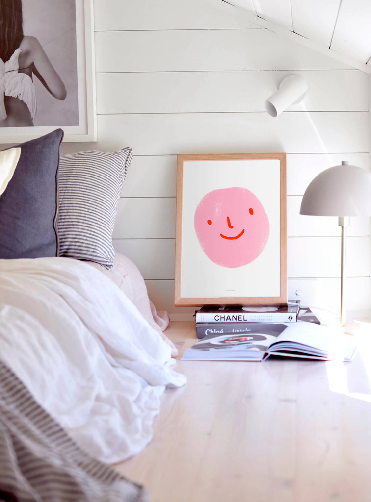 pink emoji poster with smiley face hanging in women bedroom