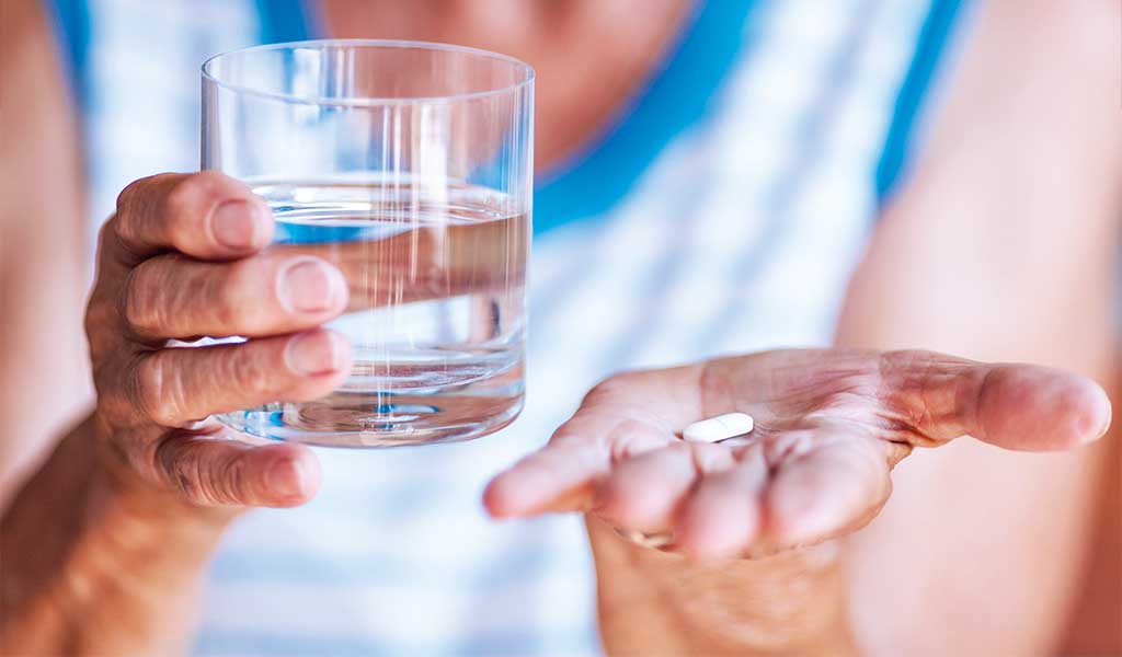 Schlafmagazin: Medikamente als Ursache für Schlafstörung, Glas Wasser und Medizin-Tablette zur Einnahme