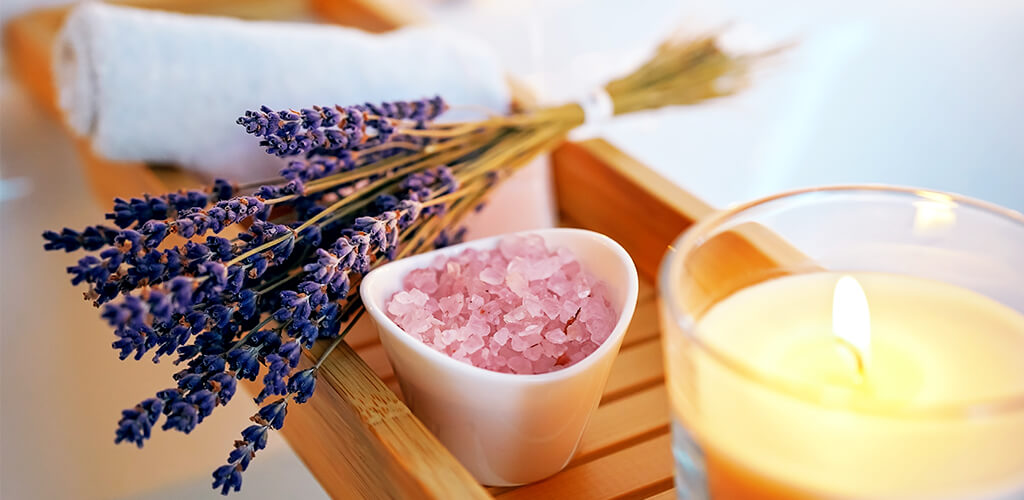 Lavendelstrauch, Duftkerze und Lavendelsalz bei einem entspannten Bad