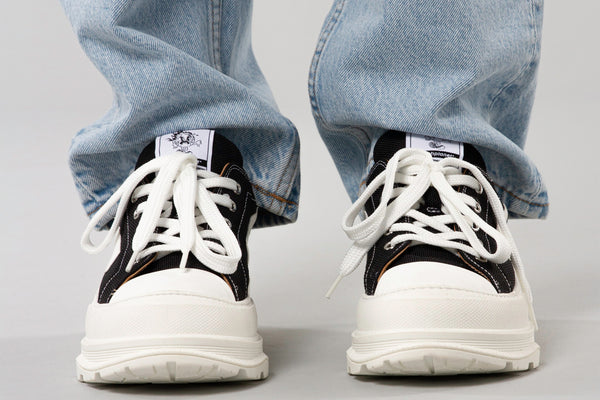 Trash Planet's chunky recycled black and white platform sneakers with a rubber toe cap worn with blue denim jeans.