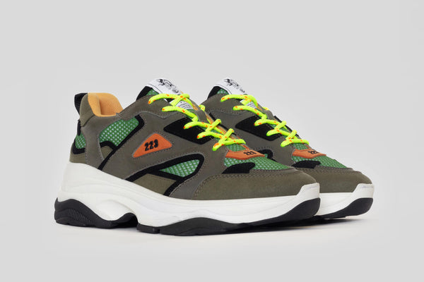 Trash Planet's new gorpcore style recycled sneaker, which is vegan and made from food waste materials like corn and apple leather. It is a green, khaki green, and bright orange colourway with orange lining and neon hiker style laces.