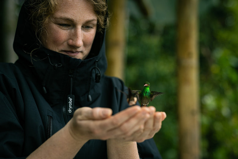 A woman wearing a dryrobe Lite with a hummingbird in her hands
