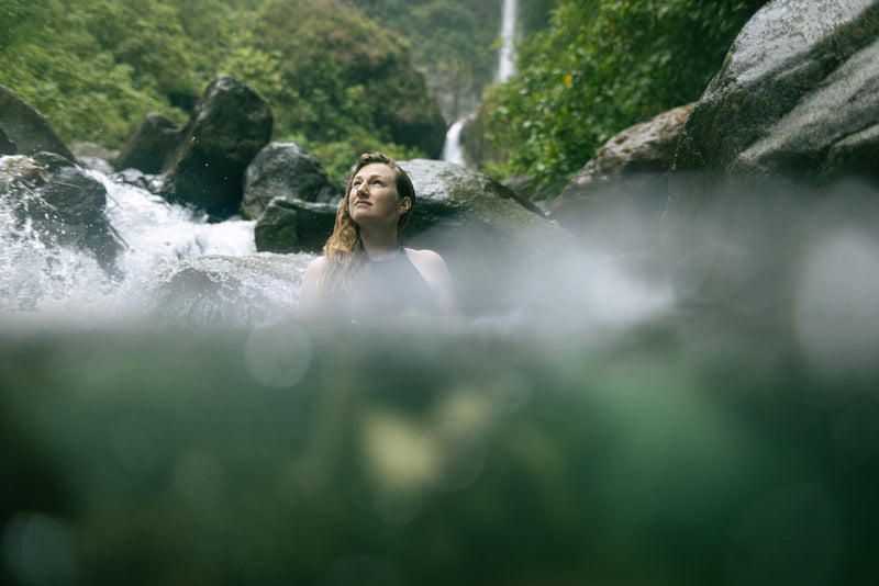 A woman swimming in a river with the rainforest in the backgroun