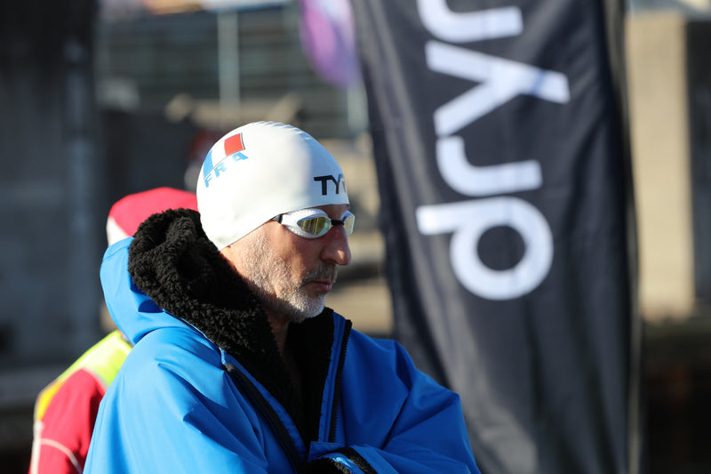A swimmer wearing a swim cap, goggles\ and dryrobe