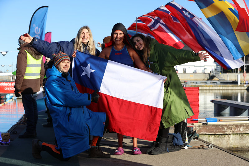 People smiling and holding the Chilean flag by an outdoor pool
