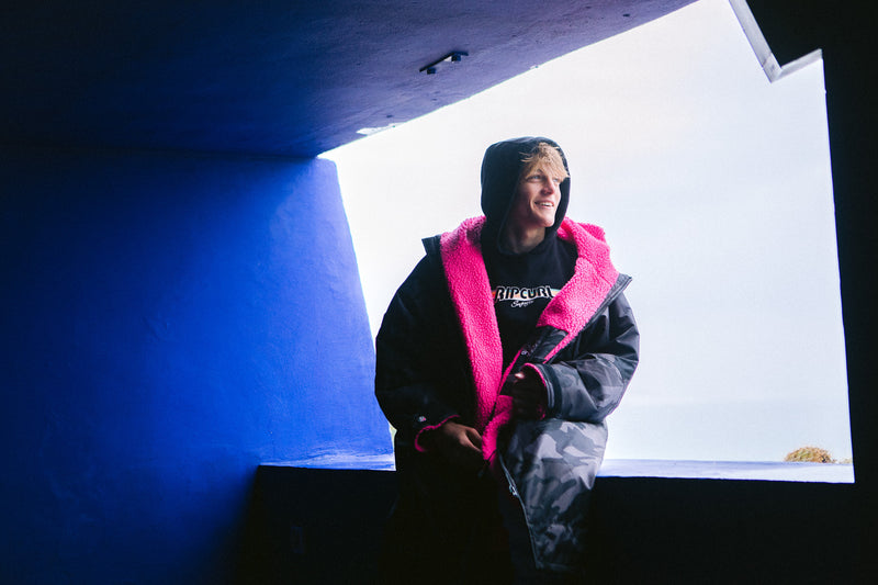 Lukas Skinner sitting down wearing a Black Camo Pink dryrobe Advance changing robe