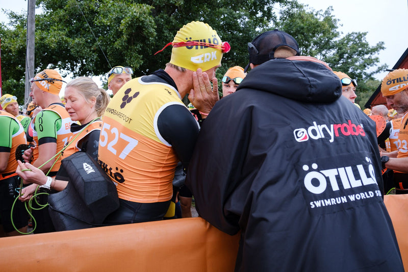A person wearing an ÖTILLÖ dyrobe® Advance talking to a competitor over the start line for the Sprint Championship 2022 