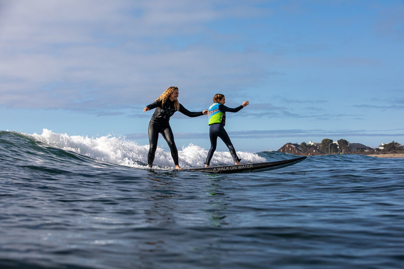 A volunteer and AWOW Athlete surfing a wave together in the sea