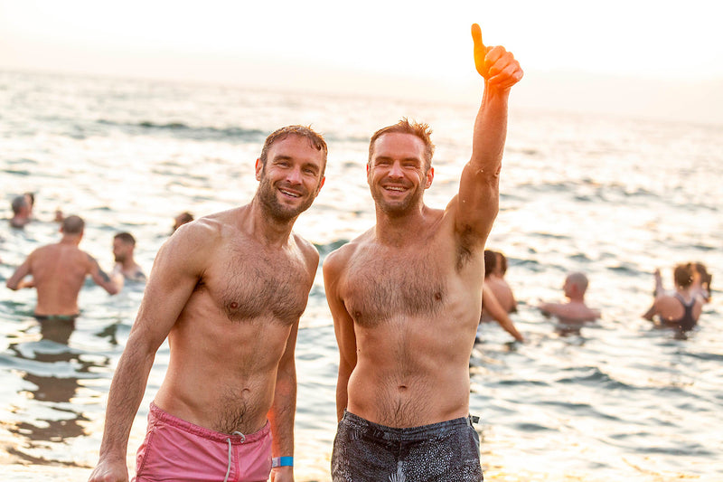 Two men stood in the sea smiling after a sea swim