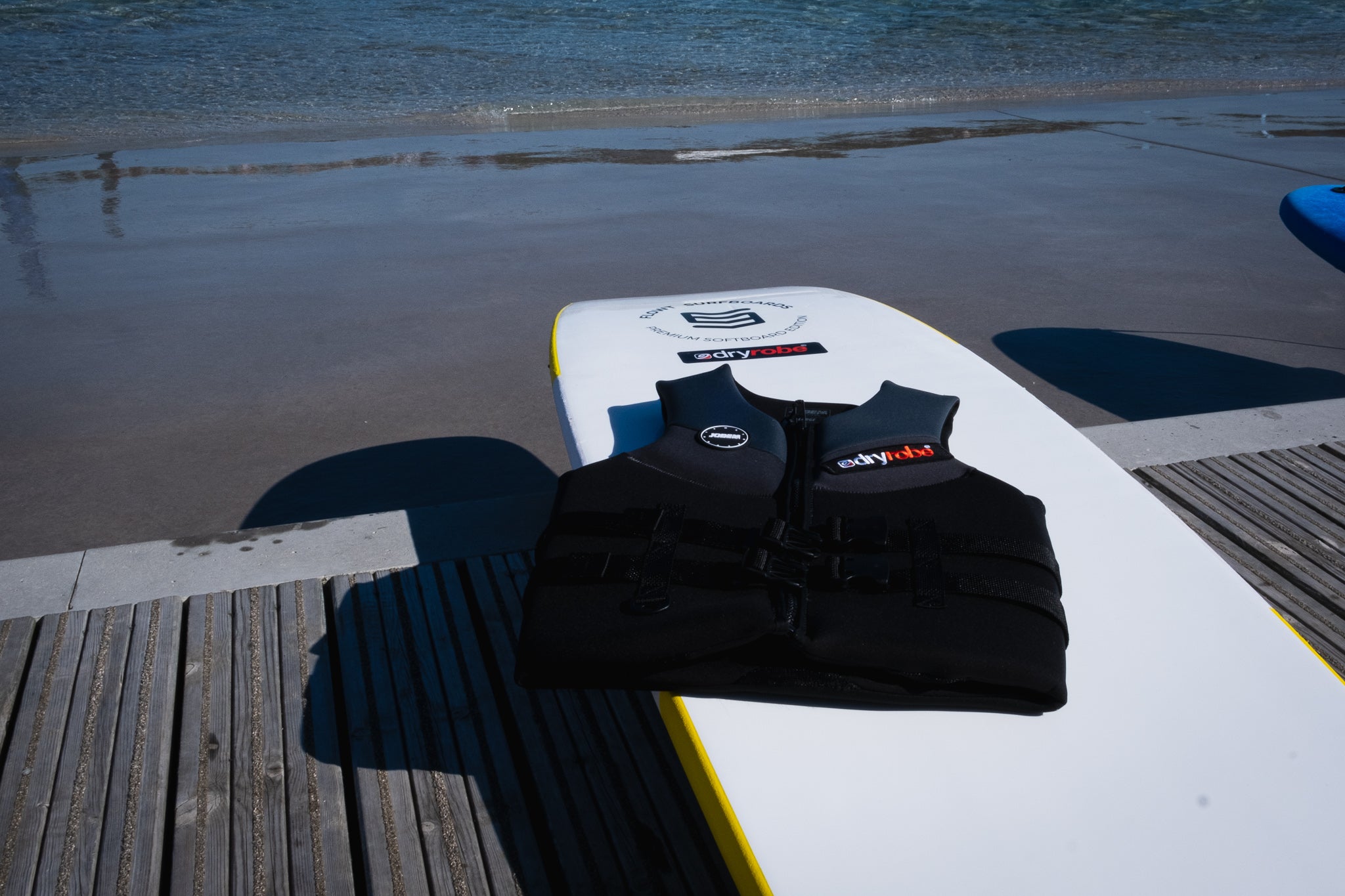 dryrobe branded Adaptive surfer board and vest, by the water at The Wave