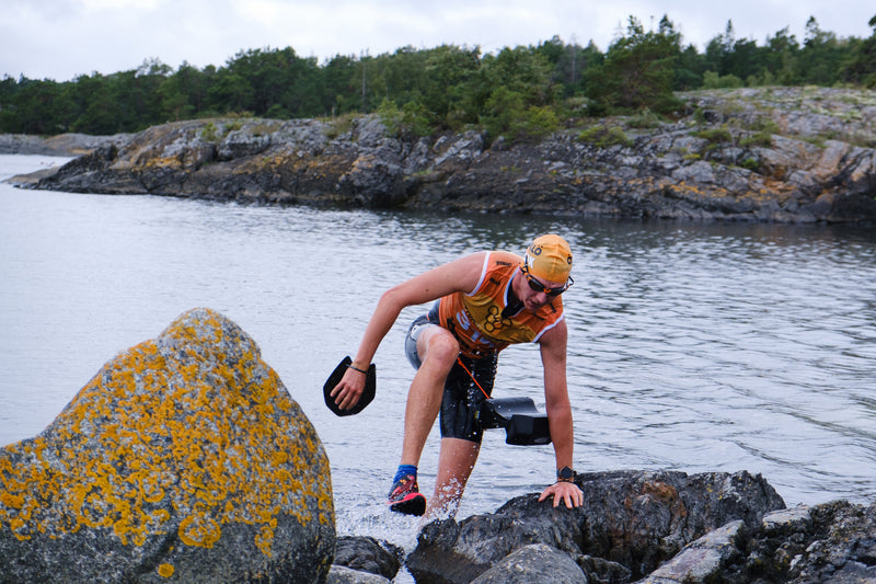 A solo swimrunner, coming ashore in an orange bib