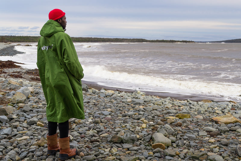 man stood on a beach looking out to see wearing a green dryrobe advance
