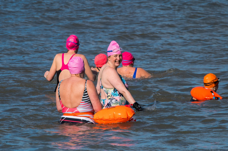 A group of open water swimmers waist deep in the sea