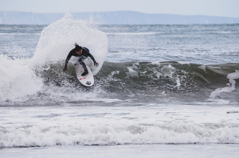 Mini Cho surfing a wave on the beach