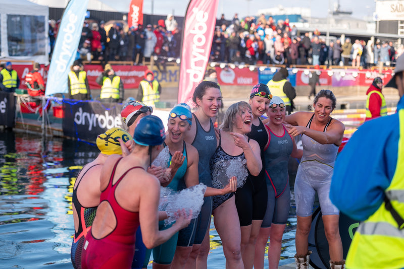 Swimmers stood in a group smiling and holding sheets of ice