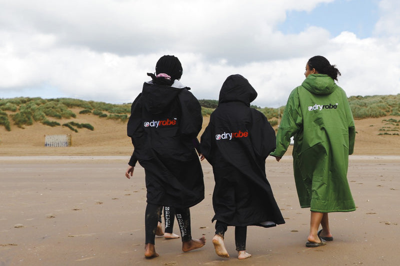 A group of children walking on the beach towards the sand dunes wearing dryrobe® Advance change robes 