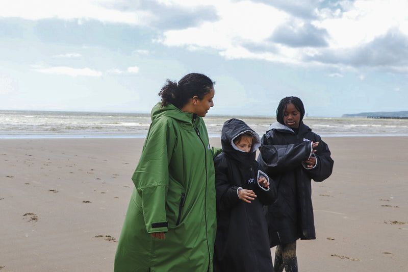 An adult and children walking on the beach in dryrobe® Advance change robes 
