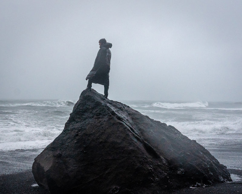 Model standing on a rock in a storm wearing a long sleeve dryrobe® Advance