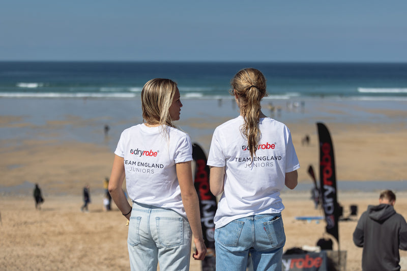 Two girls looking out over Fistral Beach wearing Team England dryrobe T shirts