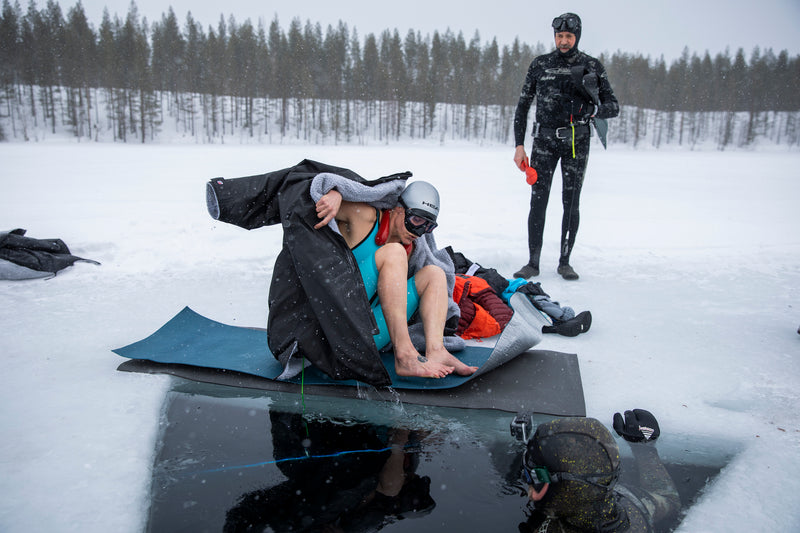 Johanna sat on the ice lake removing her dryrobe® and about to enter the ice hole