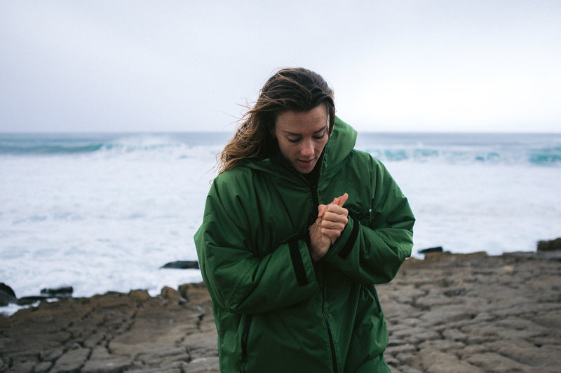 Lucy Campbell rubbing her hands together to stay warm while wearing a dryrobe by the sea
