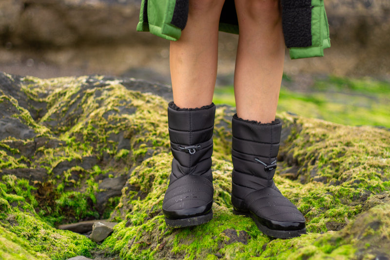 A pair of dryrobe eco thermal boots being worn on mossy rocks