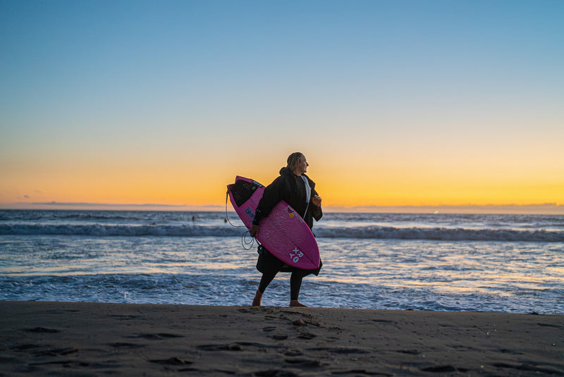 Izzi Gomez holding her surfboard in the sunset