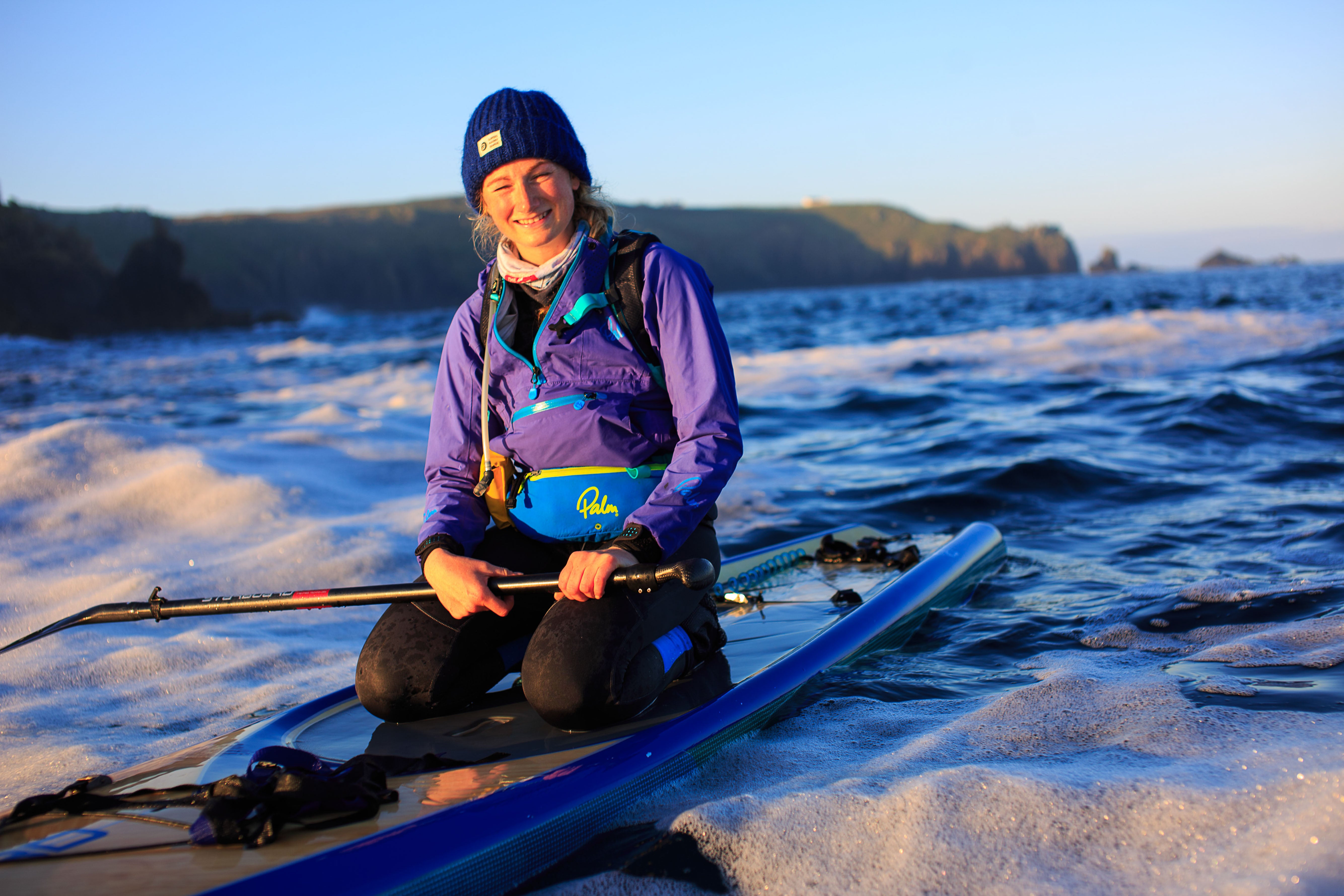 Cal Major kneeling on a paddleboard out at sea