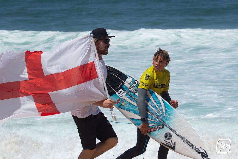 Lukas and Ben Skinner walking along the beach holding the English flag