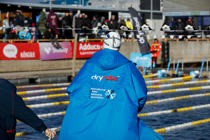 A swimmer wearing an IWSA branded dryrobe by the pool