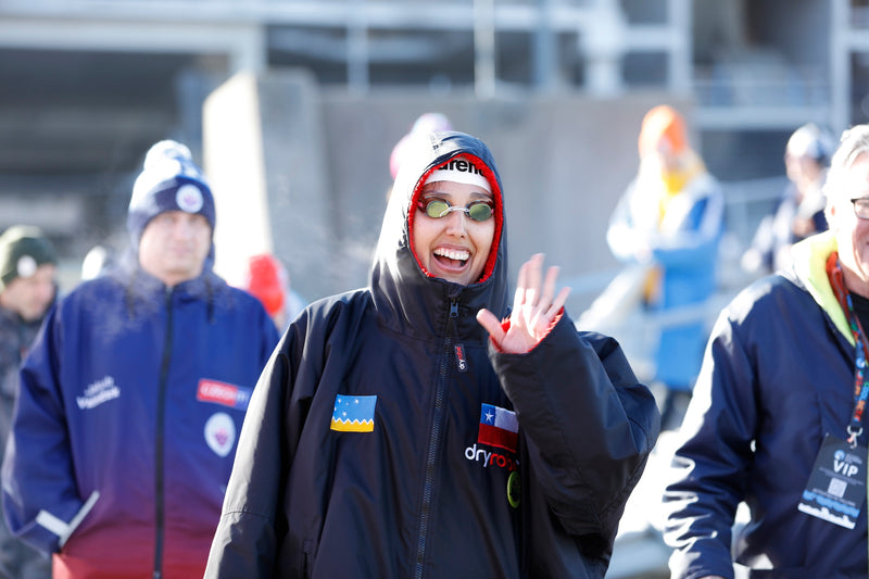 A swimmer wearing a dryrobe and waving