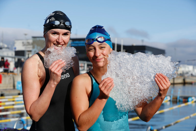 Two swimmers holding sheets of ice by an outdoor pool in Estonia