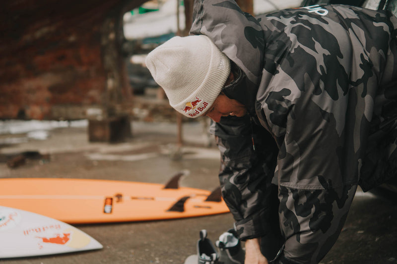  Big wave surfer Andrew Cotton in a dryrobe putting a wetsuit on 