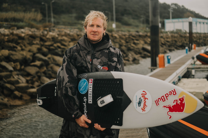 Andrew Cotton holding a surfboard