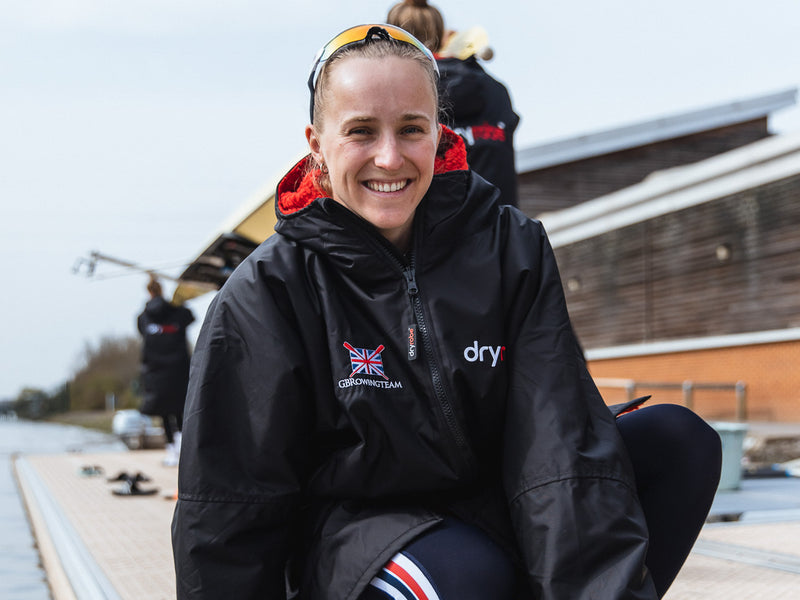 A British rower by water wearing a dryrobe 