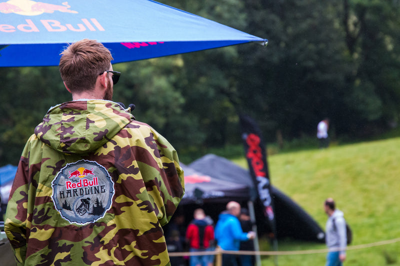 A spectator at Red Bull Hardline wearing Green Camo Limited Edition dryrobe® Advance stood by a tent 