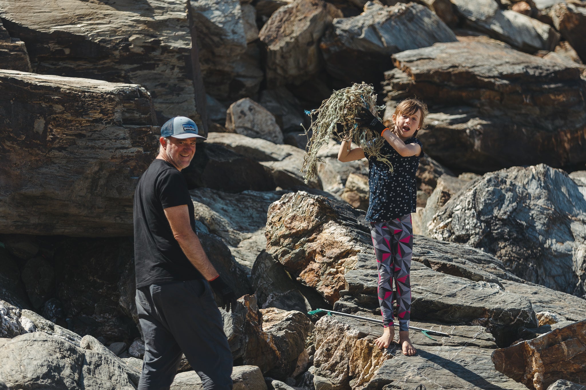 Girl holding up discarded fishing nets found on a beach clean