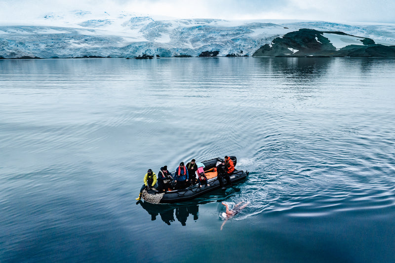 Ice marathon swimmer Bárbara Hernández Huerta swimming next to boat in Antarctic waters